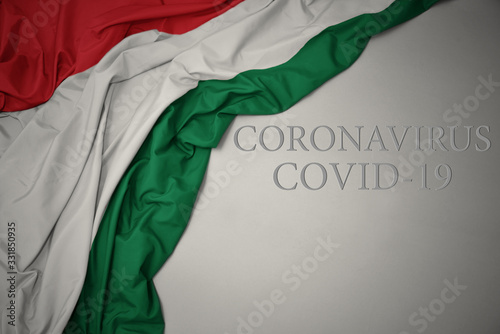 waving national flag of hungary on a gray background with text coronavirus covid-19 . concept.