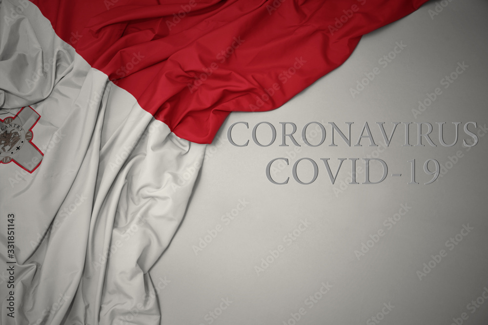 waving national flag of malta on a gray background with text coronavirus covid-19 . concept. waving national flag of malta on a gray background with text coronavirus covid-19 . concept.