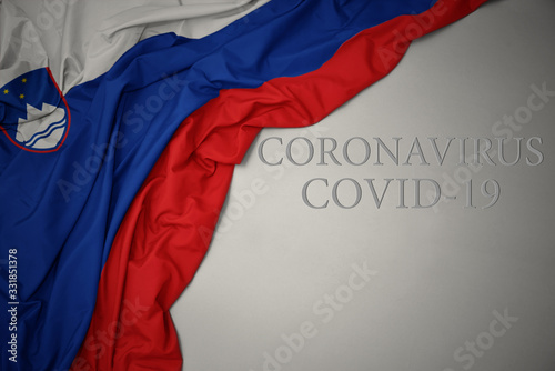 waving national flag of slovenia on a gray background with text coronavirus covid-19 . concept.