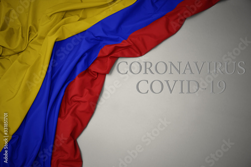 waving national flag of colombia on a gray background with text coronavirus covid-19 . concept.