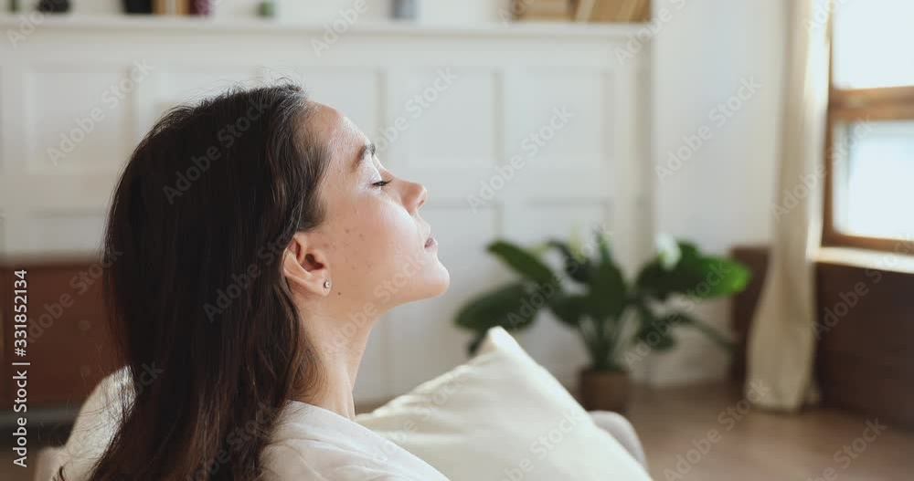 Serene mindful pretty young woman taking deep breath of fresh air meditating with eyes closed at home. Calm lady doing yoga exercise feels no stress and life balance, peace of mind concept. Side view Serene mindful pretty young woman taking deep breath of fresh air meditating with eyes closed at home. Calm lady doing yoga exercise feels no stress and life balance, peace of mind concept. Side view