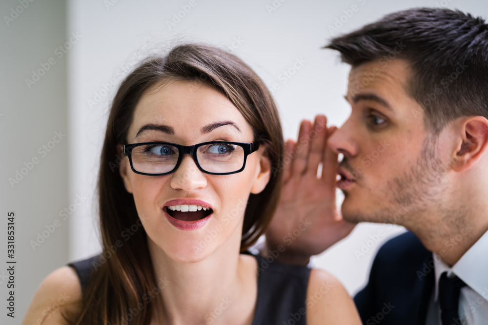 Businessman Whispering Into Female Partner's Ear Businessman Whispering Into Female Partner's Ear