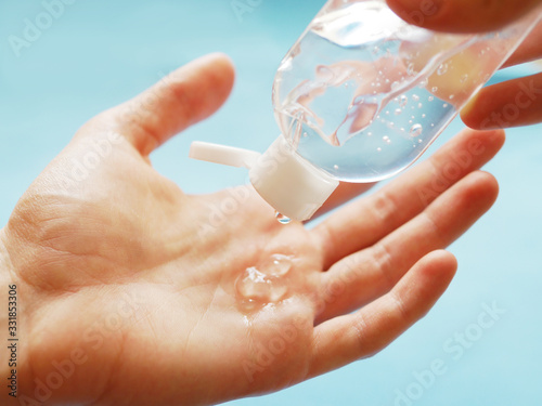 Female hand with antibacterial hand gel on a blue background. A means of protection against viruses. photo