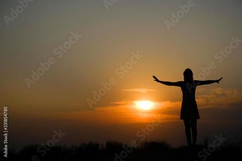 Silhouette of a girl on top of a mountain at sunset. © alexeytsurkan