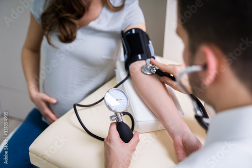 Doctor Measuring Blood Pressure Of Pregnant Woman