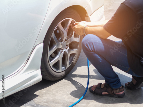 man put air into the car tire cause of low air pressure in the oil station.