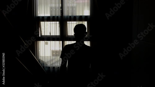 Alone man silhouette staring at the window closed with curtains in house. People with depression concept.