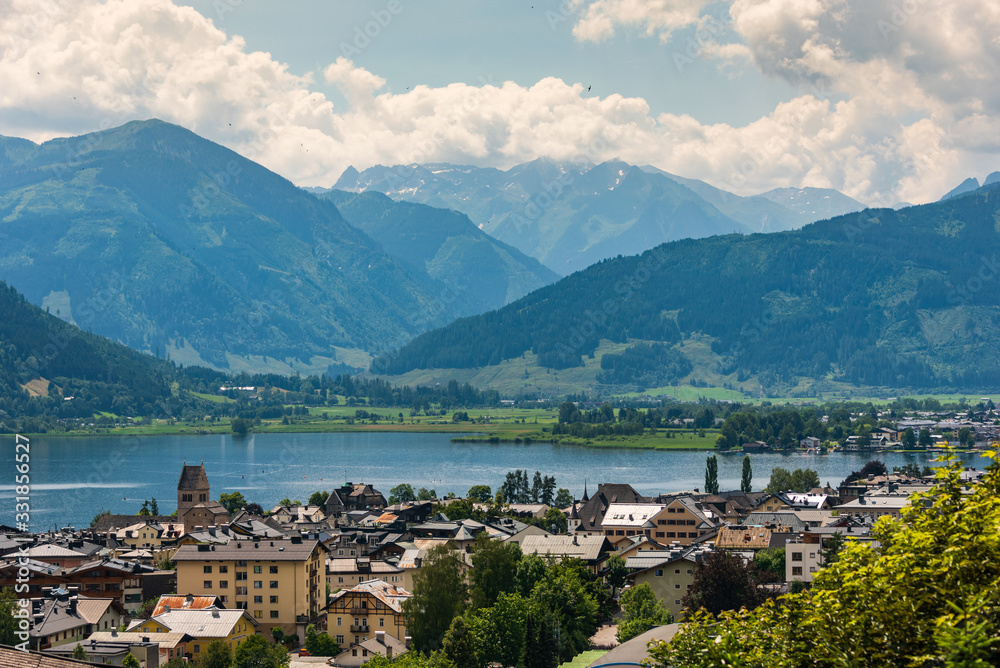 Cityscape of alpine city Zell am See with Zeller Lake in summer. Above view of Tirol lake, meadows and Tirol Alps Mountains in Austria.