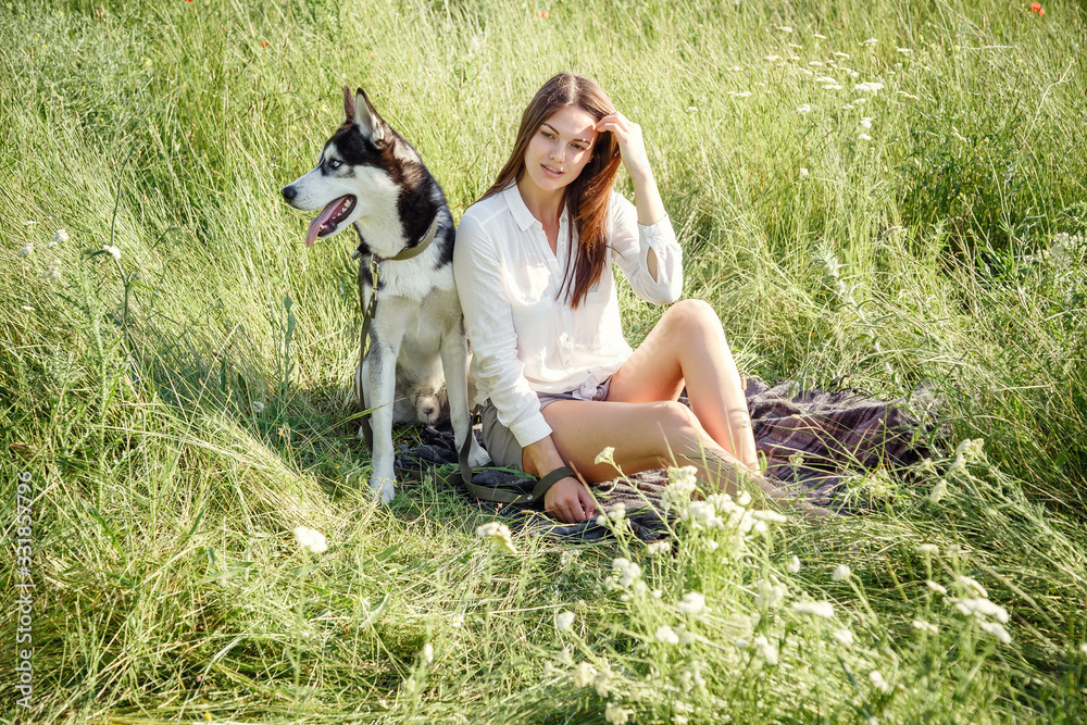Beautiful woman playing with husky dog outdoors at park.