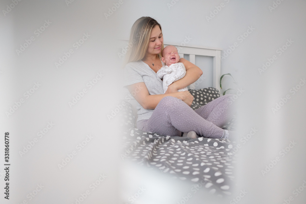 Home portrait of a newborn baby with mother and dad on the bed. Mom holding and kissing her child. Home portrait of a newborn baby with mother and dad on the bed. Mom holding and kissing her child.