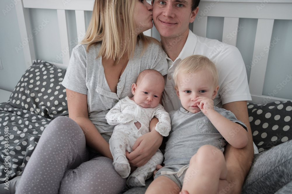 Family portrait: young mom and dad with his 2 years old son and 2 month old baby Family portrait: young mom and dad with his 2 years old son and 2 month old baby