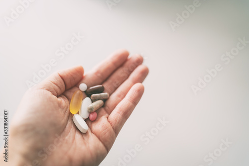 Vitamins, minerals and supplements pill capsules woman taking many pills top view of hand holding tablets. photo