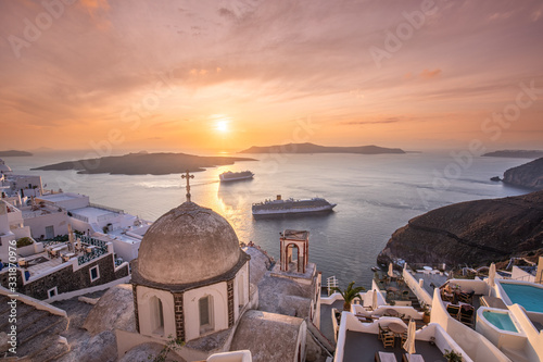 Beautiful summer landscape, luxury travel background. Amazing evening view of Fira, caldera, volcano of Santorini, Greece with cruise ships at sunset. Cloudy dramatic sky.