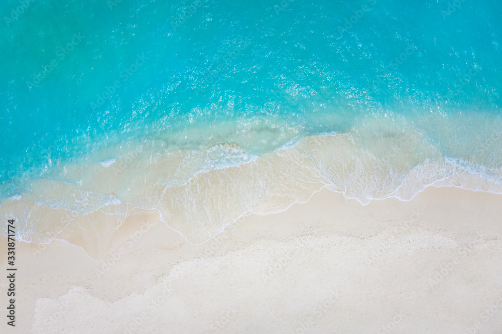 Summer seascape beautiful waves, blue sea water in sunny day. Top view from drone. Sea aerial view, amazing tropical nature background. Beautiful bright sea with waves splashing and beach sand concept