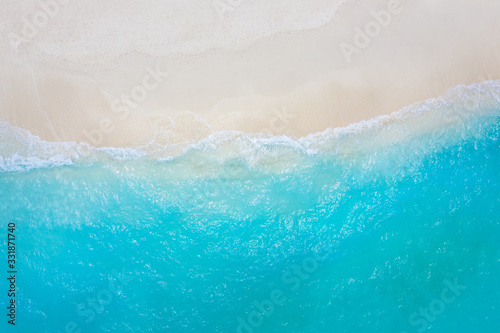 Summer seascape beautiful waves  blue sea water in sunny day. Top view from drone. Sea aerial view  amazing tropical nature background. Beautiful bright sea with waves splashing and beach sand concept