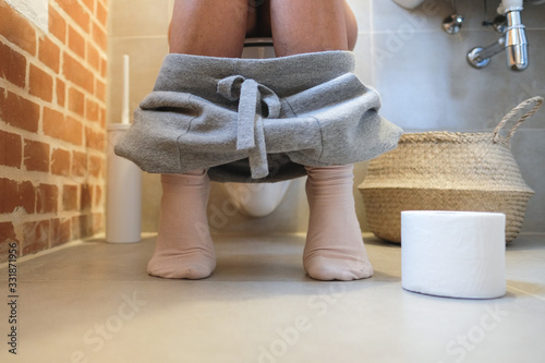 Frau sitzt auf wc mit Toilettenpapier photo
