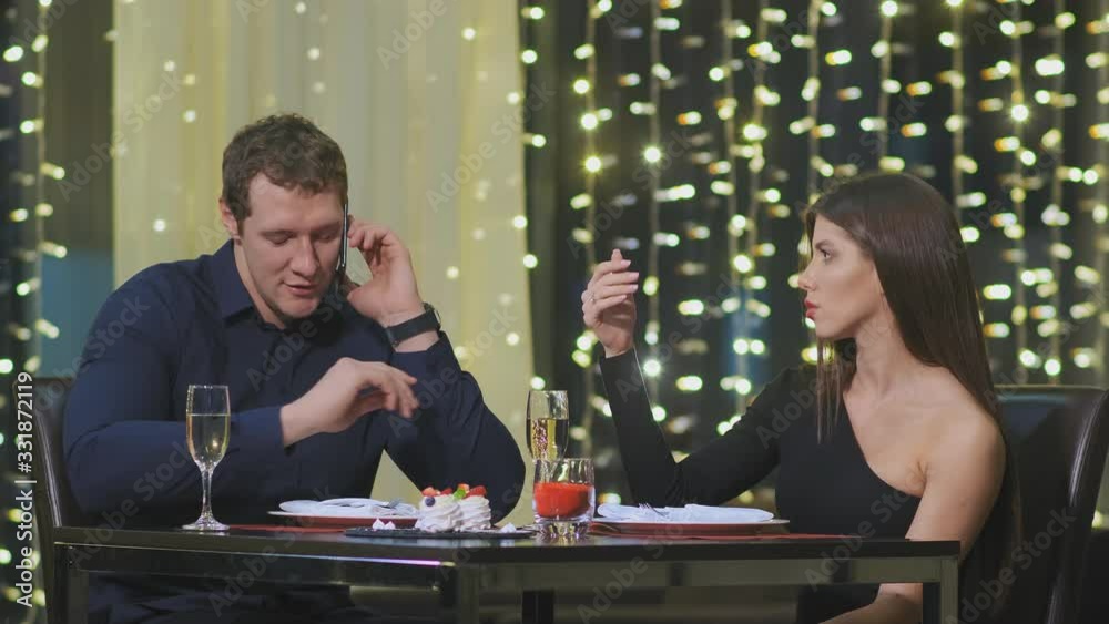 man sits at table and solves work issues during date and offended girlfriend sits with him and conflict man sits at table and solves work issues during date and offended girlfriend sits with him and conflict