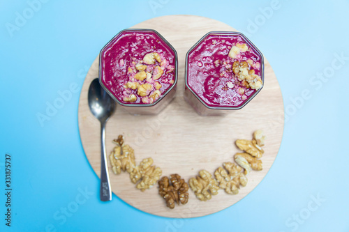 cranberry smoothie on a blue background with slices of nuts