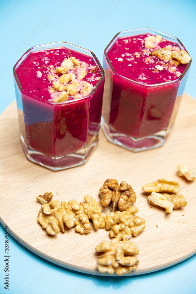 cranberry smoothie on a blue background with slices of nuts