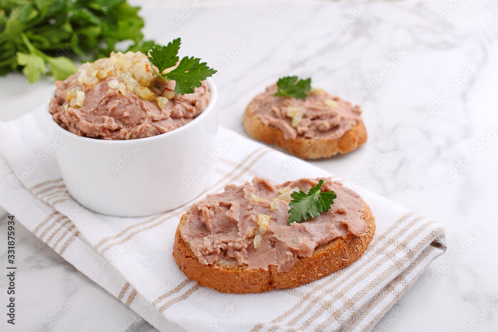 Bean paste with fried onions in a white ceramic form on a marble background.