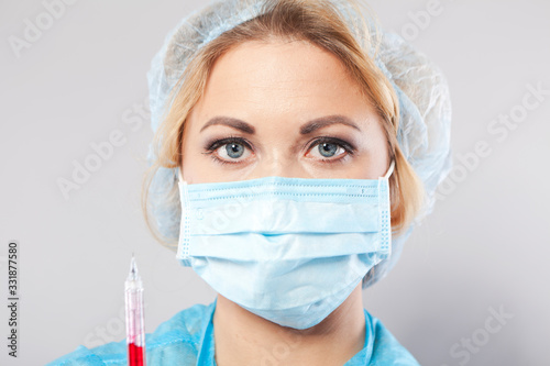 Masked young nurse with a syringe in her hands. Nurse.