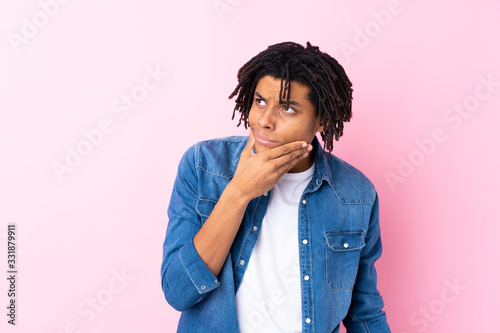 Young African American man with jean shirt over isolated pink background thinking an idea