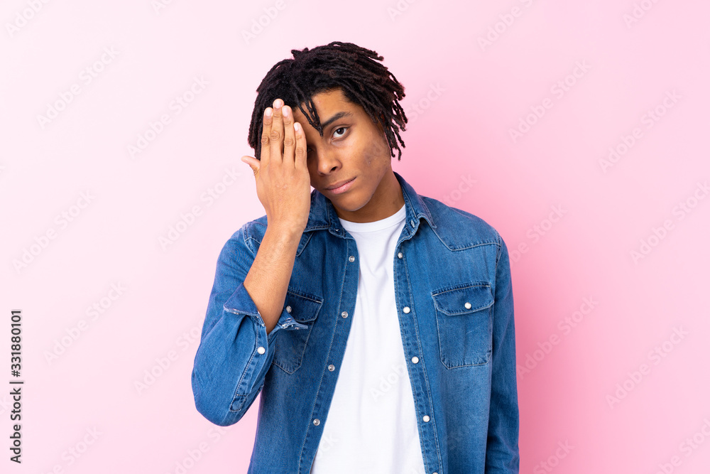 Young African American man with jean shirt over isolated pink background covering a eye by hand Young African American man with jean shirt over isolated pink background covering a eye by hand