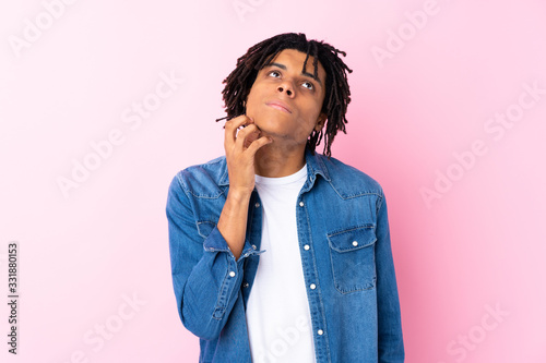 Young African American man with jean shirt over isolated pink background thinking an idea