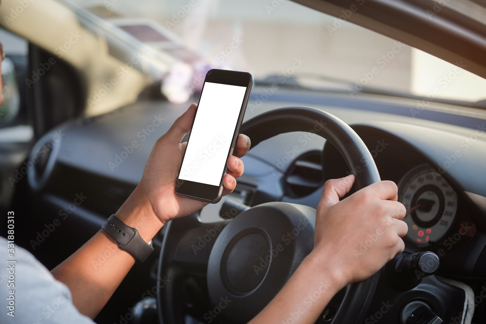 Cropped shot view The driver uses the phone while driving. Modern smart phone with round edges. Isolated screen for mockup. Car navigation display in background. 