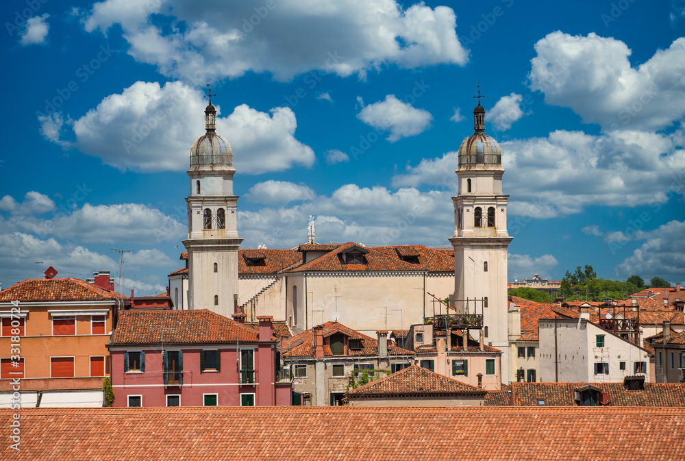 Church bell towers with domes under clouds in Venice