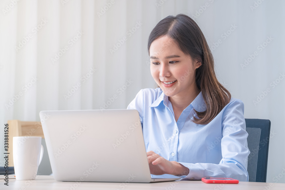 Attractive Asian woman works from home with laptop on desk in bedroom. Young girl smiling with happiness face while reading at computer screen. Telecomuting, freelancer and modern lifestyle concept. Attractive Asian woman works from home with laptop on desk in bedroom. Young girl smiling with happiness face while reading at computer screen. Telecomuting, freelancer and modern lifestyle concept.