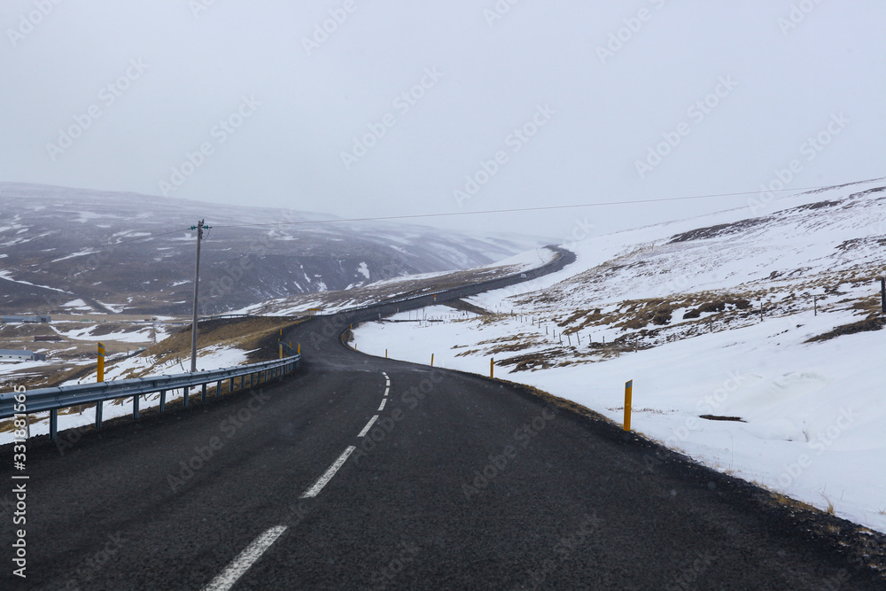 road in winter landscape in Iceland. Asphalt road with a side full of snow road in winter landscape in Iceland. Asphalt road with a side full of snow
