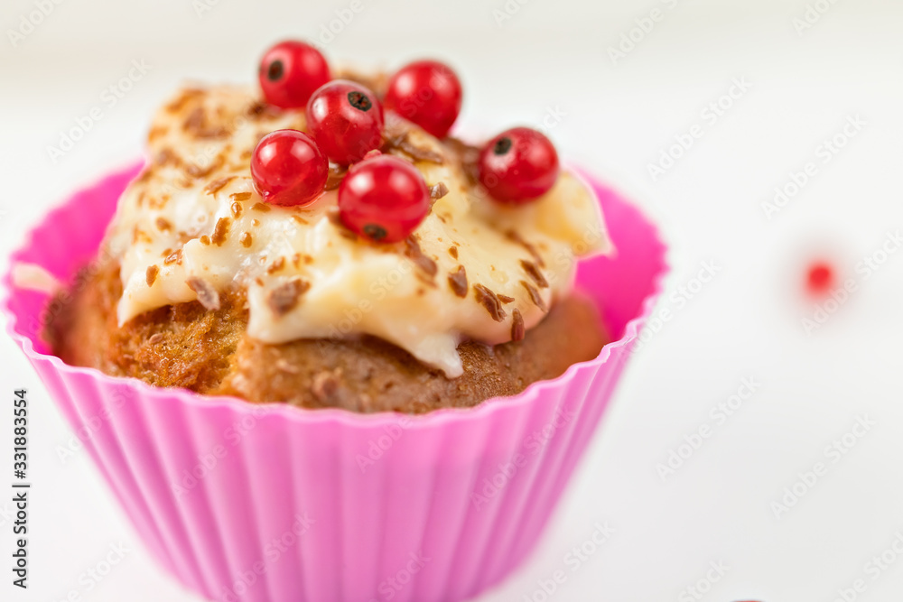 Summer seasonal Home pastries: cupcake in silicone shape is decorated with red currant berries and cream sauce. Maffins in pink individual form for baking. berries against the background. Summer seasonal Home pastries: cupcake in silicone shape is decorated with red currant berries and cream sauce. Maffins in pink individual form for baking. berries against the background.