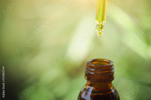 Hand holding bottle of Cannabis oil in pipette, CBD cannabis OIL, natural herb, hemp product, medical marijuana concept.
