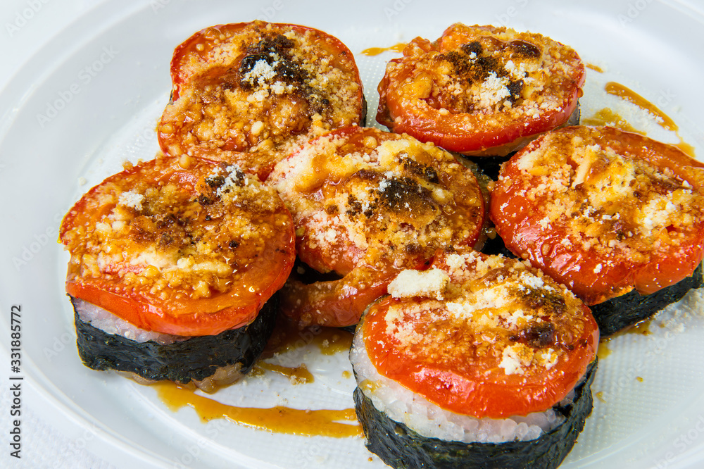 Traditional rice Japanese rolls covered with fried tomato and cheese. Lie on a plastic disposable plate Traditional rice Japanese rolls covered with fried tomato and cheese. Lie on a plastic disposable plate