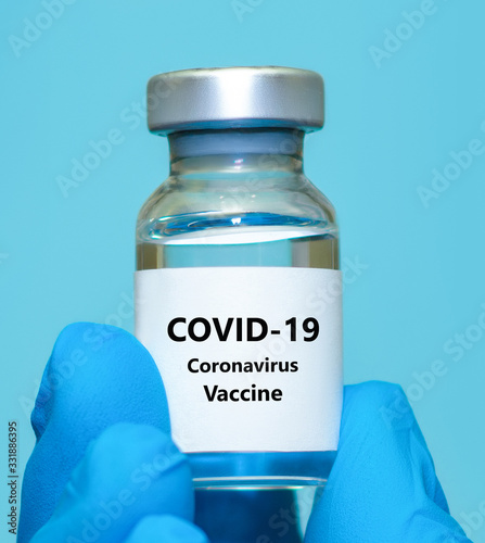 Hand of a doctor or nurse in a glove holds a coronavirus vaccine.The concept of vaccination, medicine, healthcare.