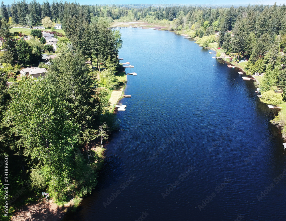 Lovely Lake Holm Water Access Site in springtime with the surrounding forest and homes and the sky and clouds in Auburn Washington