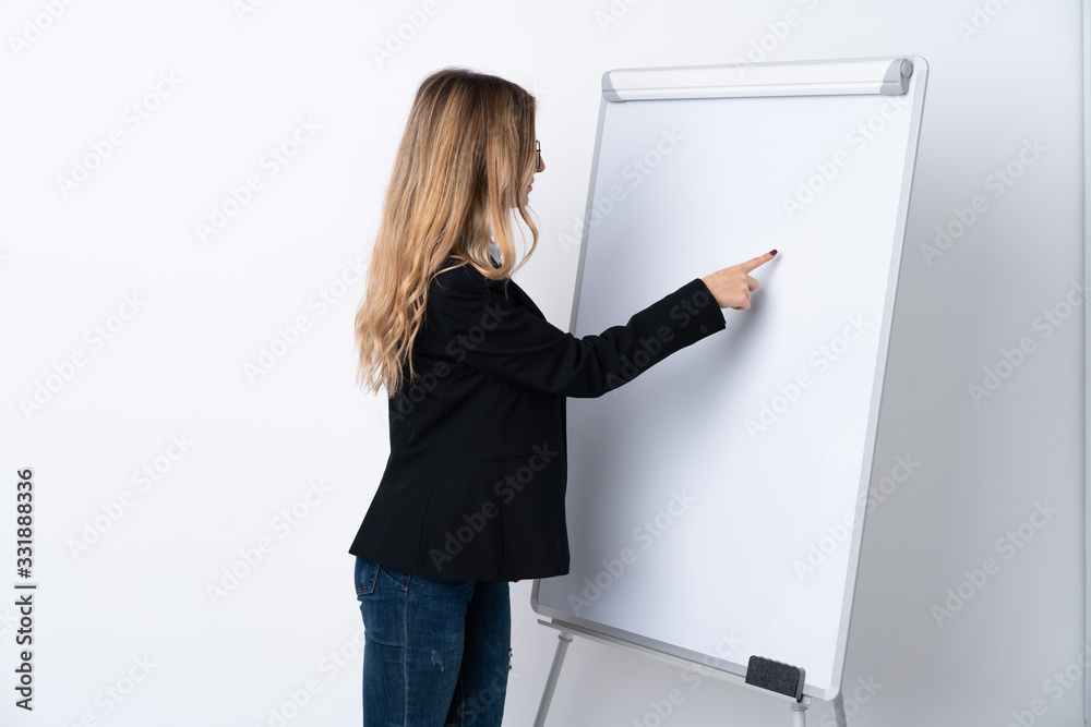 Young woman over isolated white background giving a presentation on white board and writing in it Young woman over isolated white background giving a presentation on white board and writing in it