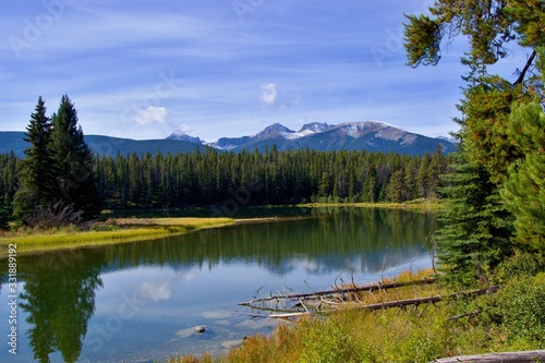 Beautiful lake high in the mountains surrounded by forest. Blue sky  white clouds. Canadian Rockies.