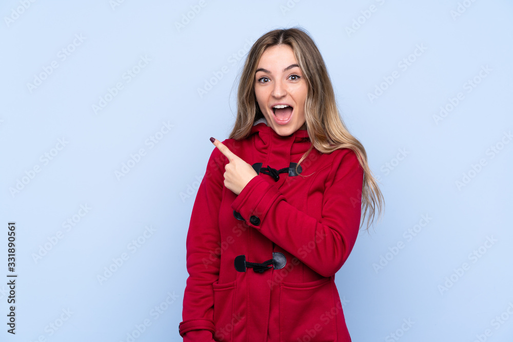 Young woman with winter coat over isolated blue background pointing finger to the side Young woman with winter coat over isolated blue background pointing finger to the side