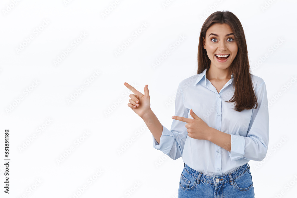 Surprised young successful working woman in blue blouse look impressed as seeing something unexpecting and awesome, pointing finger left sharing great news with you, white background Surprised young successful working woman in blue blouse look impressed as seeing something unexpecting and awesome, pointing finger left sharing great news with you, white background