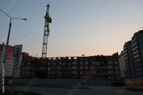 unfinished building near which there is a construction crane against the blue sky