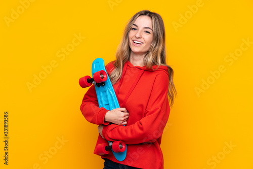 Young woman over isolated yellow background with a skate with happy expression