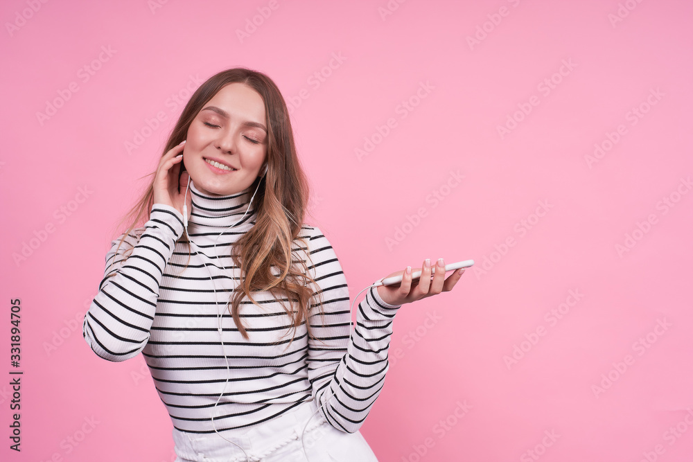 Happy cheerful girl in headphones and a phone on a pink background. Happy cheerful girl in headphones and a phone on a pink background.