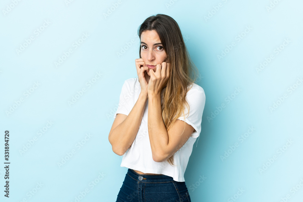 Young caucasian woman over isolated background nervous and scared putting hands to mouth