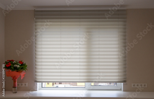 Pleated shades size XL, 50mm fold, close up on the window, white color, white background. Modern pleated blinds, luxury sun protection and window decoration.