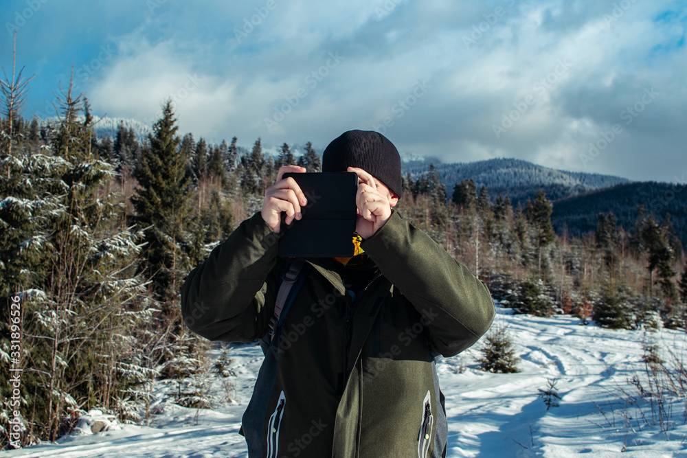 Man with beard, wearing winter clothes talking on the phone. A hiker goes in the winter mountains with a backpack. Beautiful mountains in winter time