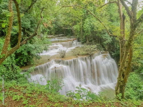 view of silky waterfall flowing on the cliff around with green forest background, Chat Kaew (floor 4th), Huai Mae Khamin Waterfall, Kanchanaburi, west of Thailand.