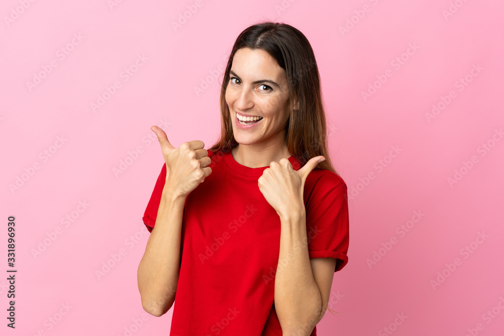Young caucasian woman isolated on pink background with thumbs up gesture and smiling Young caucasian woman isolated on pink background with thumbs up gesture and smiling