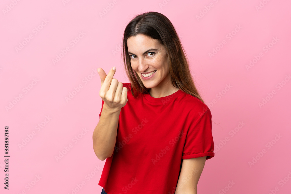 Young caucasian woman isolated on pink background making money gesture